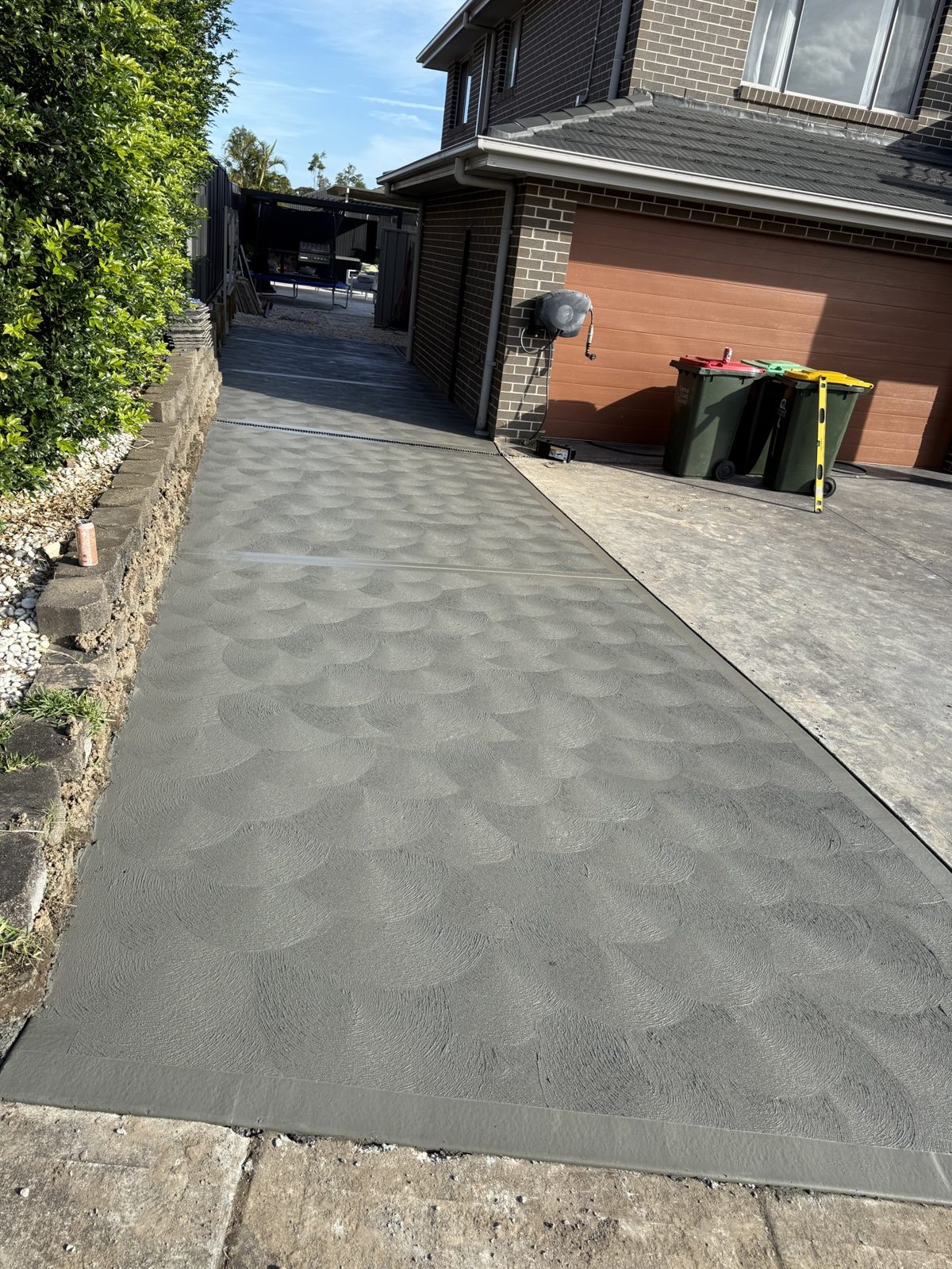 Patterned concrete driveway running down the side of a home by EAB Concreting, Hunter Valley