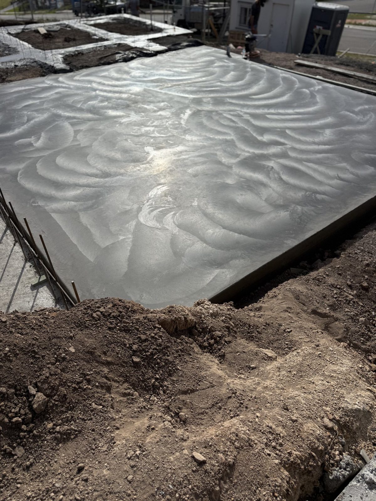 Freshly finished plain concrete slab beside an excavated site by EAB Concreting, Hunter Valley